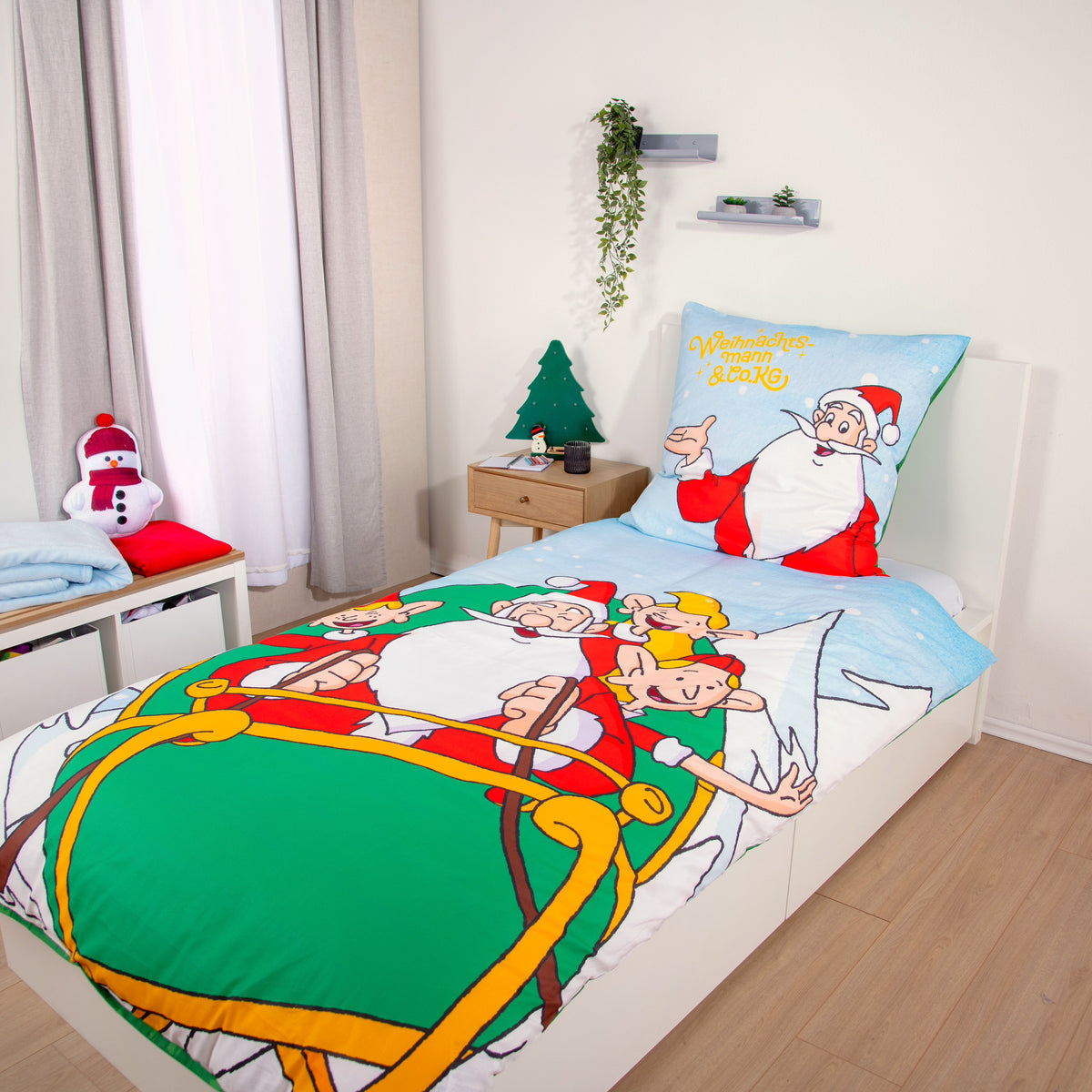 Weihnachtsmann & Co. KG Bettwäsche ‘Nordpol-Helden’ aus Flanell auf einem Einzelbett, daneben ein Nachttisch mit kleinem Tannenbaum