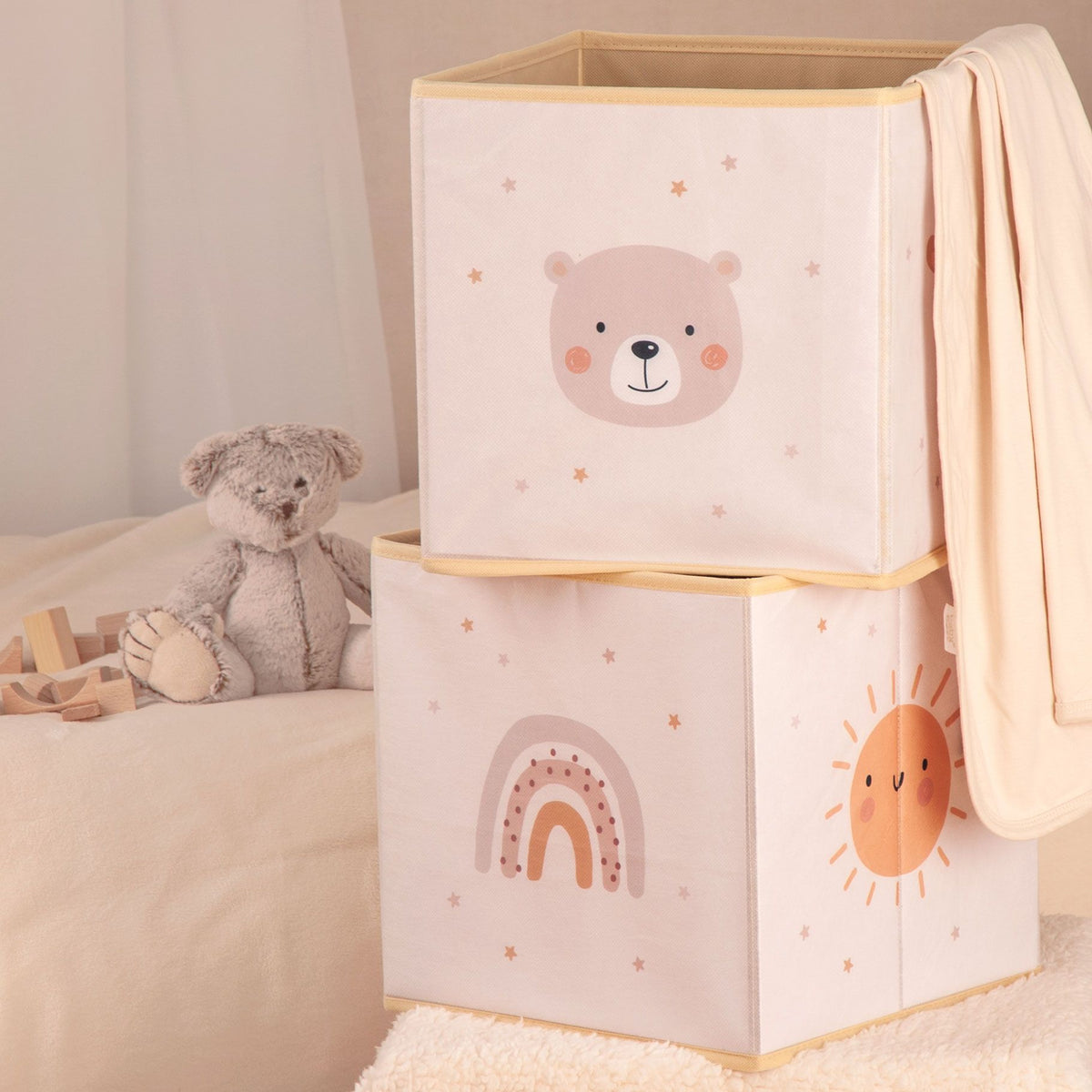 Zwei gestapelte Aufbewahrungsboxen ‘Little Friends’ mit Bär und Regenbogen neben einem Teddy