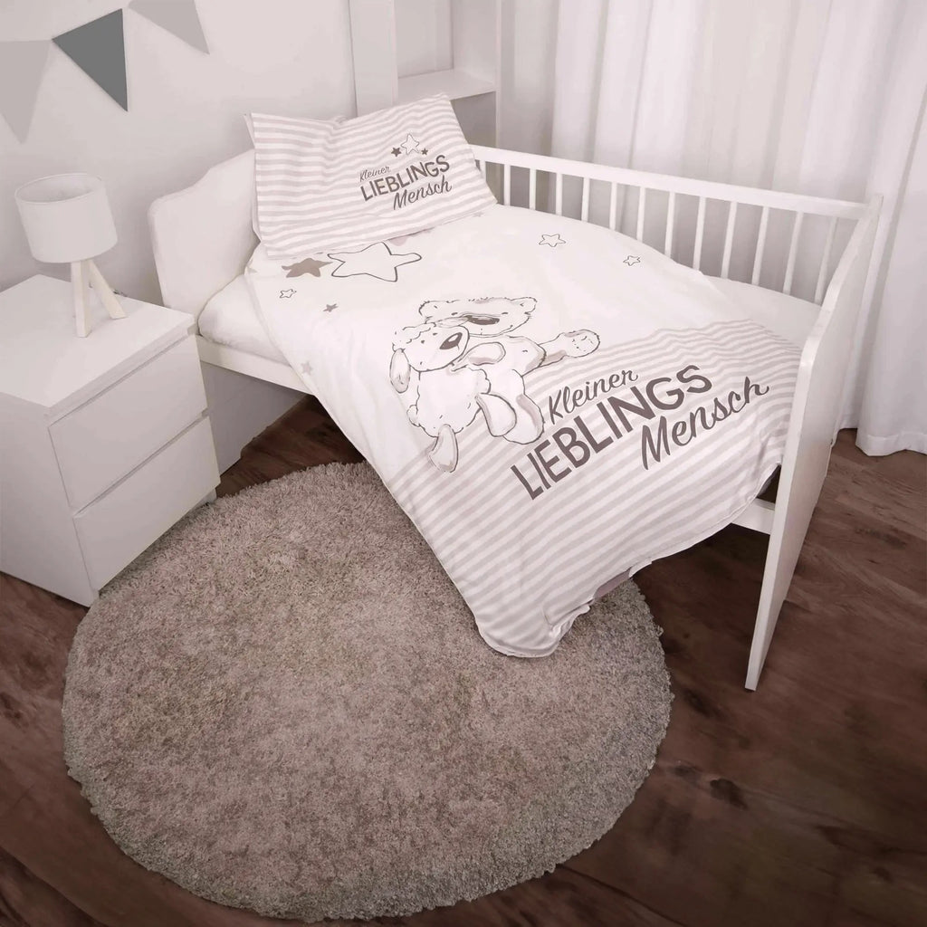 babybest Bettwäsche ‘Kleiner Lieblingsmensch’ Beige in einem weißen Gitterbett, Bettbezug mit Bär, Lamm und Schriftzug, Kissen gestreift mit Schriftzug