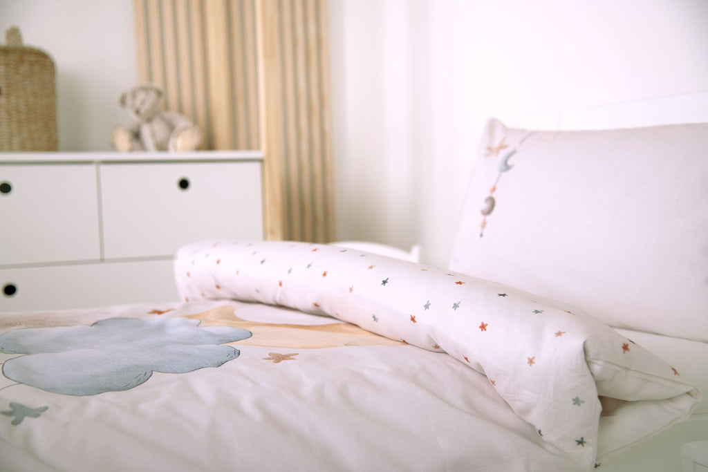 Bettwäsche ‘Moon and Stars’ seitlich auf einem Kinderbett mit umgeschlagener Sternen-Wendeseite