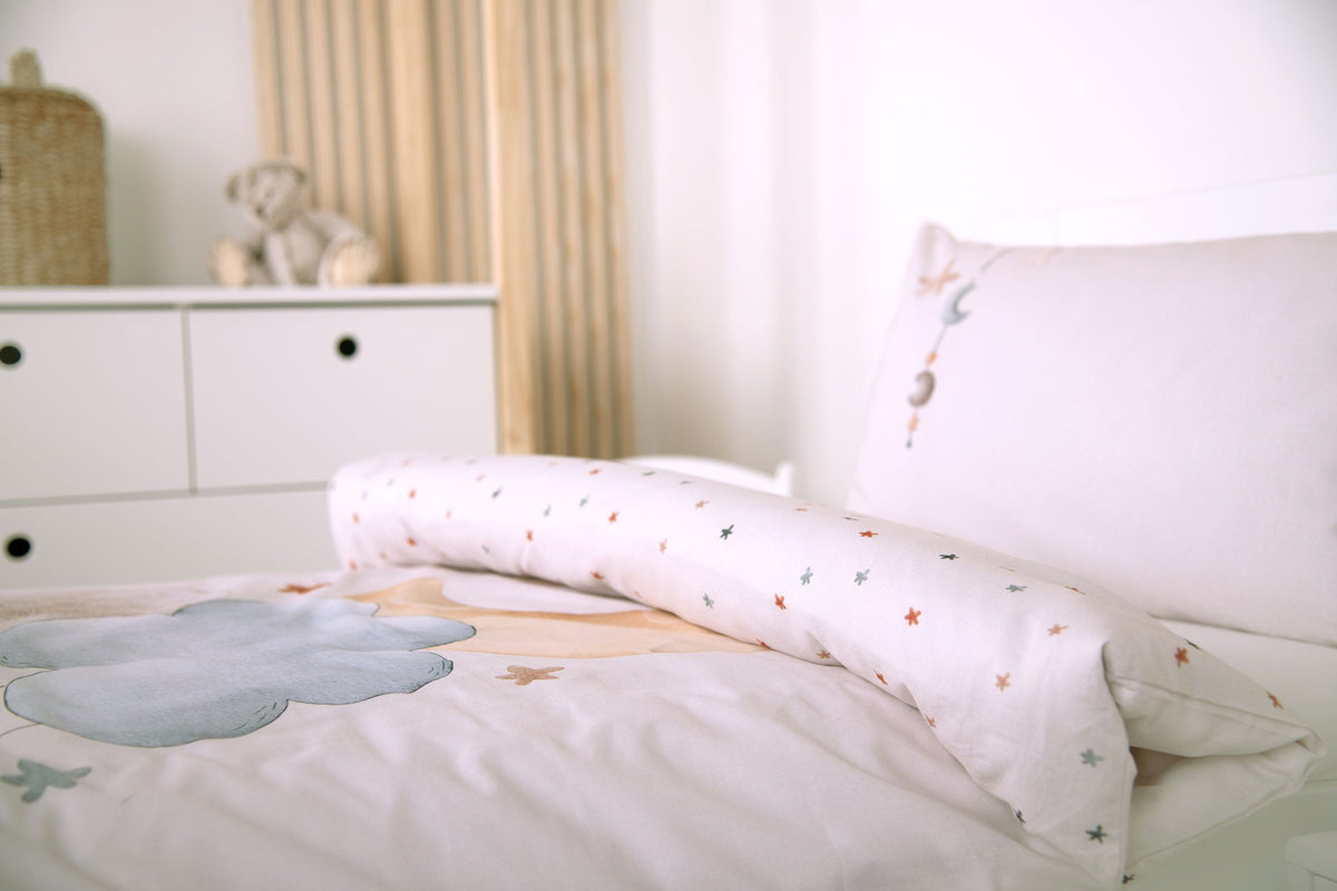 Bettwäsche ‘Moon and Stars’ seitlich auf einem Kinderbett mit umgeschlagener Sternen-Wendeseite