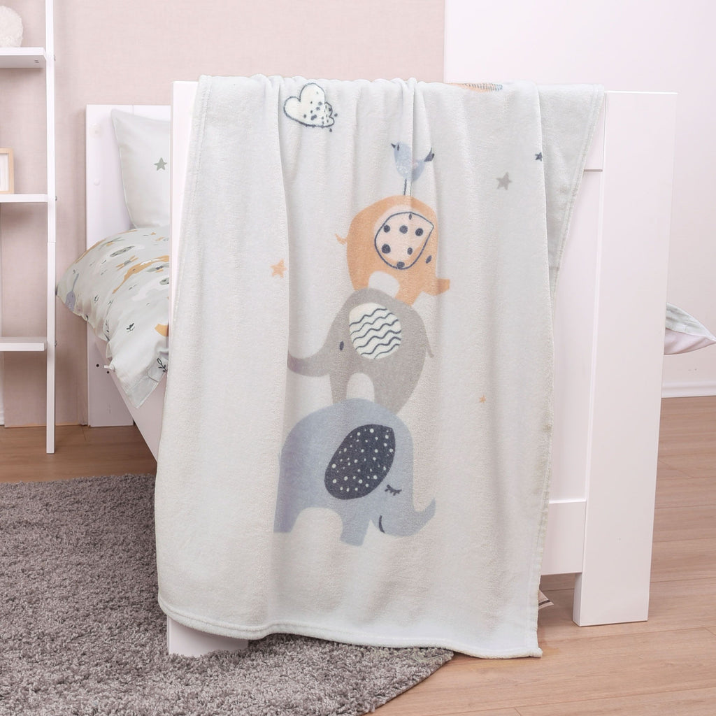 babybest Kuscheldecke ‘Elephants’ über dem Rand eines weißen Babybetts