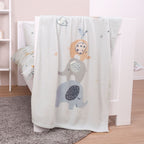 babybest Kuscheldecke ‘Elephants’ über dem Rand eines weißen Babybetts
