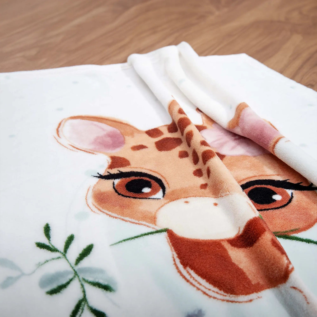 Nahaufnahme der Giraffe mit grünem Halm auf der Kuscheldecke