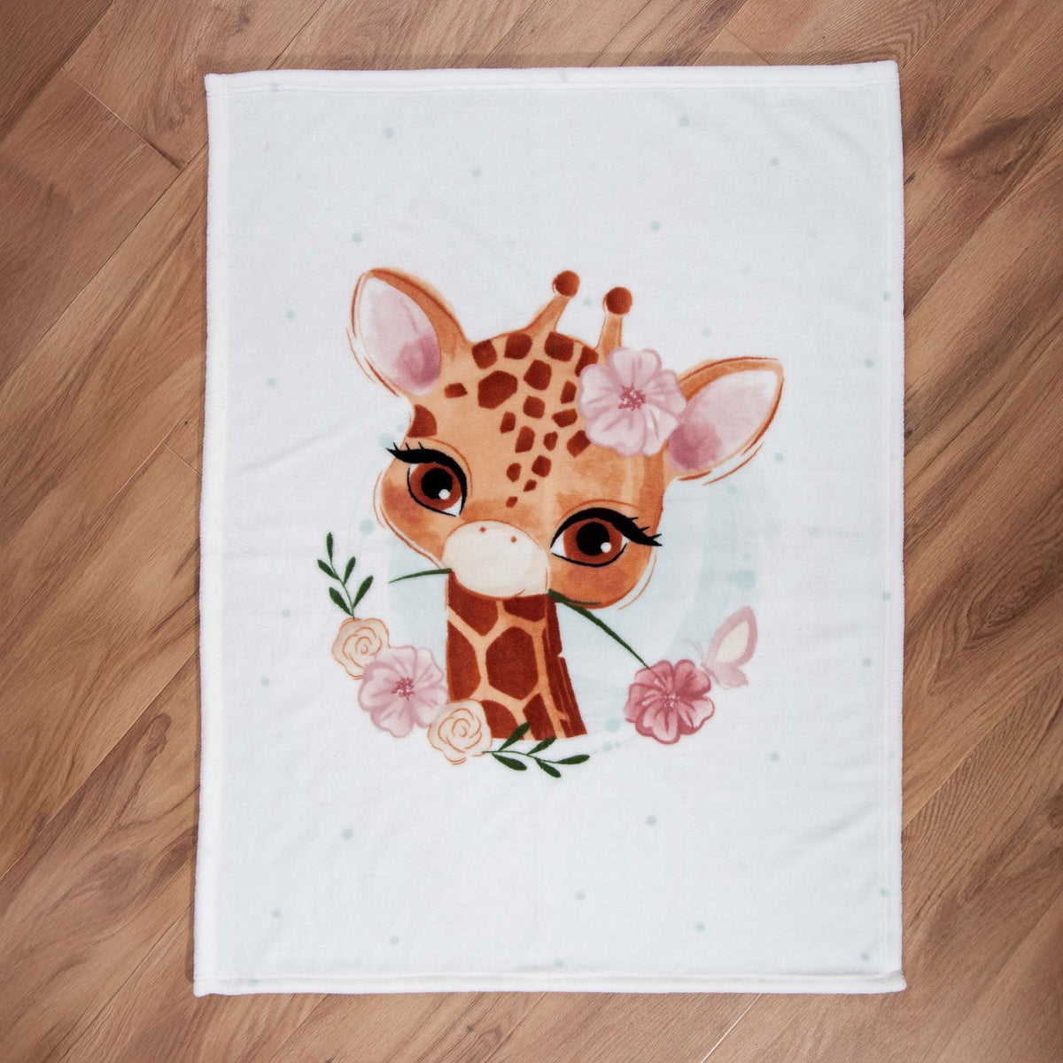 babybest Kuscheldecke ‘Giraffe’ ausgebreitet auf einem Holzboden