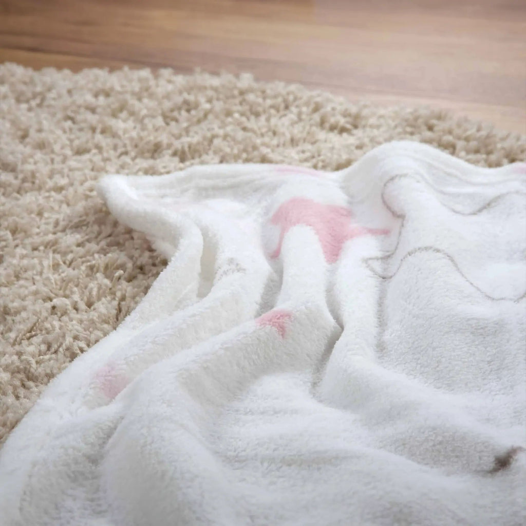 Kuscheldecke ‘Kleiner Lieblingsmensch’ in Rosa auf einem hellen Hochflorteppich