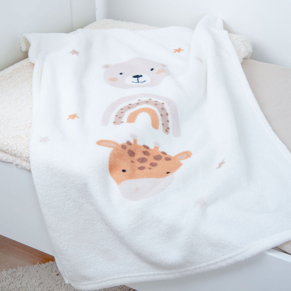 Kuscheldecke ‘Little Friends’ mit Bär, Regenbogen und Giraffe über einer Bettkante