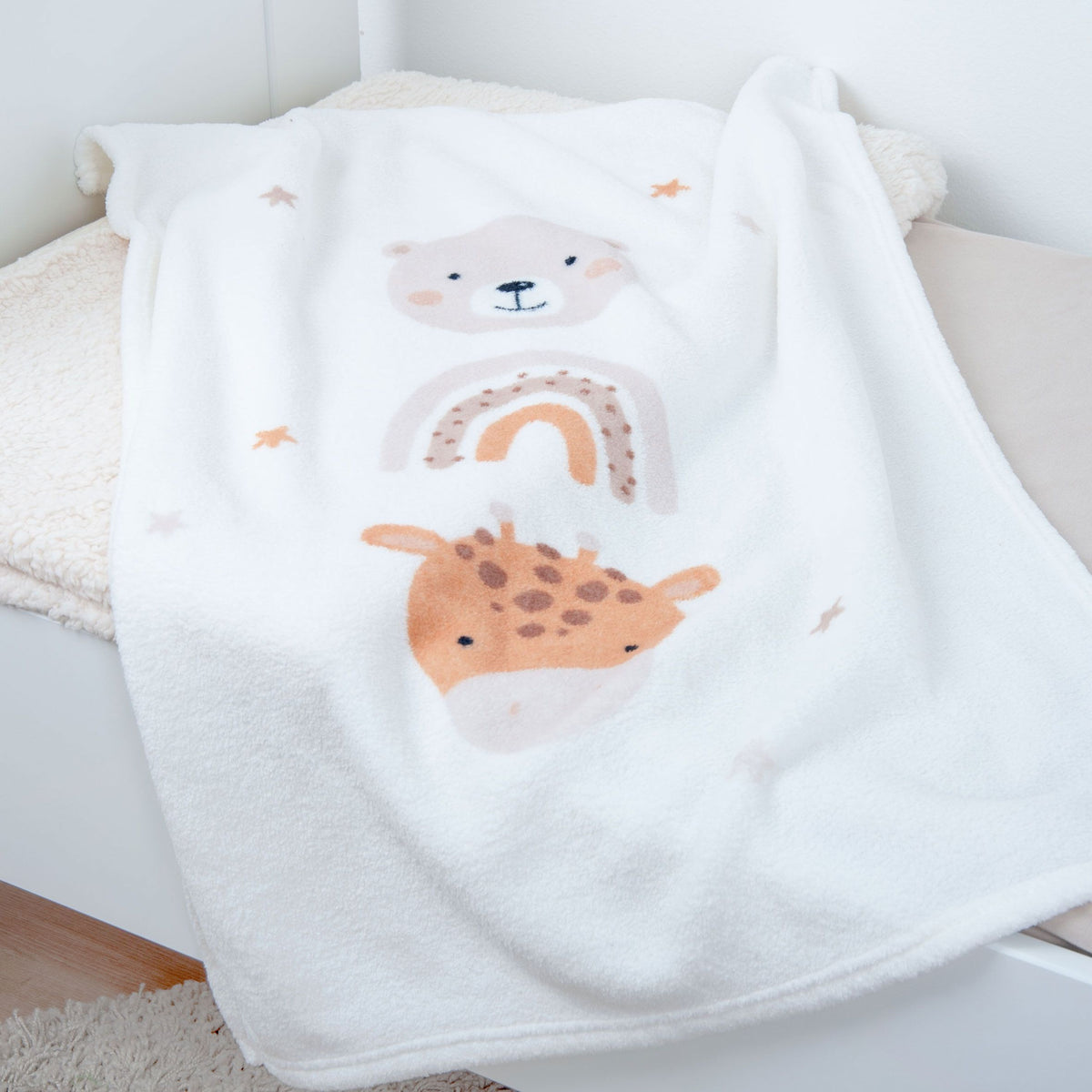 Kuscheldecke ‘Little Friends’ mit Bär, Regenbogen und Giraffe über einer Bettkante