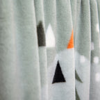 Tannenspitzen und orange Dreiecke auf der Kuscheldecke in Nahaufnahme