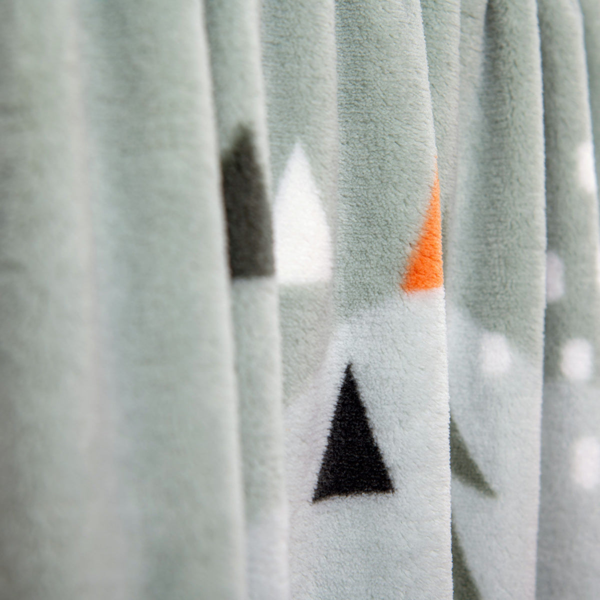 Tannenspitzen und orange Dreiecke auf der Kuscheldecke in Nahaufnahme