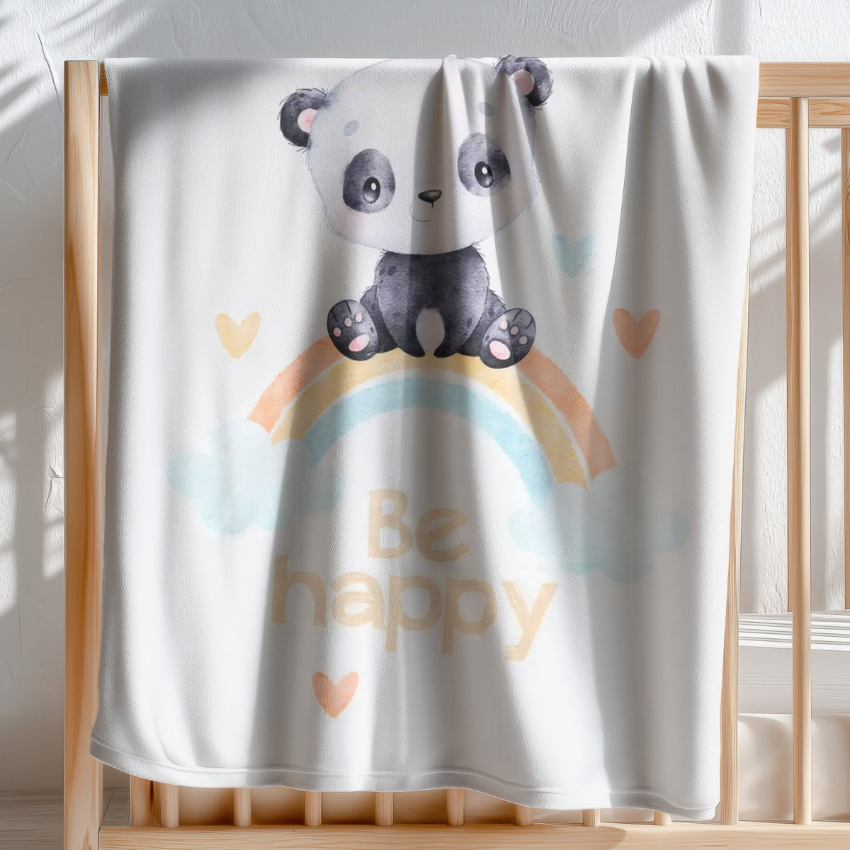babybest Kuscheldecke ‘Regenbogen Panda’ 75 x 100 cm über der Stange eines Gitterbetts, Panda auf dem Regenbogen mit Schriftzug Be happy und Herzen