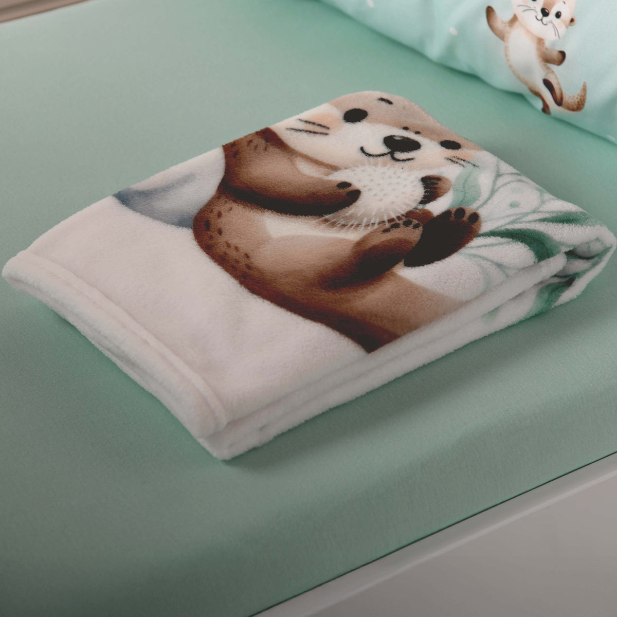 Zusammengelegte Kuscheldecke ‘Schnuffel-Otter’ auf einem mintfarbenen Laken