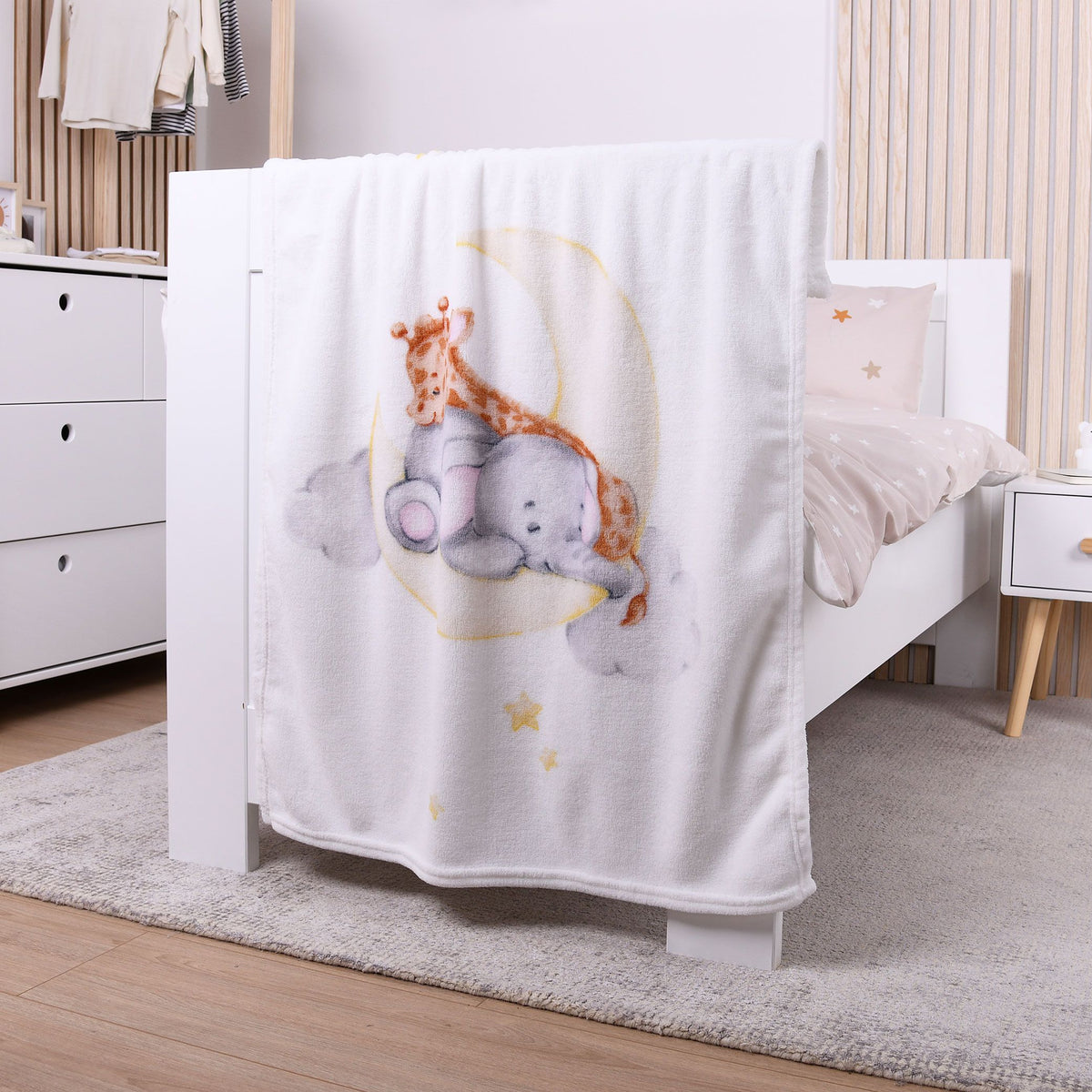 babybest Kuscheldecke ‘Sleeping on the Moon’ über dem Gitter eines Kinderbetts