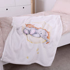 babybest Kuscheldecke ‘Sleeping on the Moon’ auf einem Kinderbett mit beiger Bettwäsche