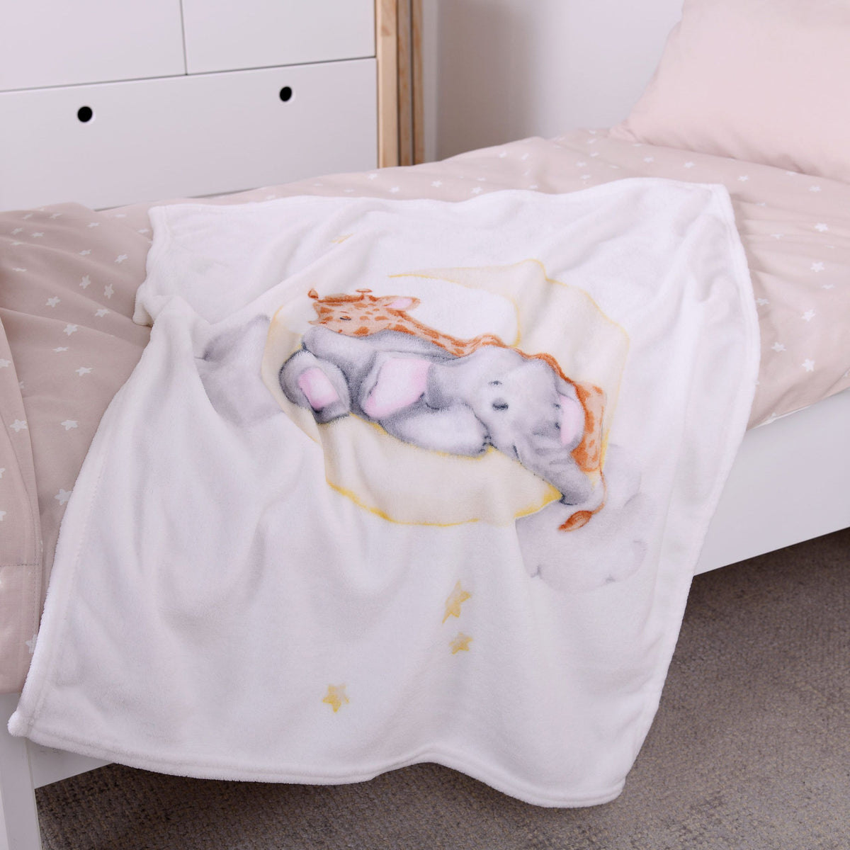 babybest Kuscheldecke ‘Sleeping on the Moon’ auf einem Kinderbett mit beiger Bettwäsche