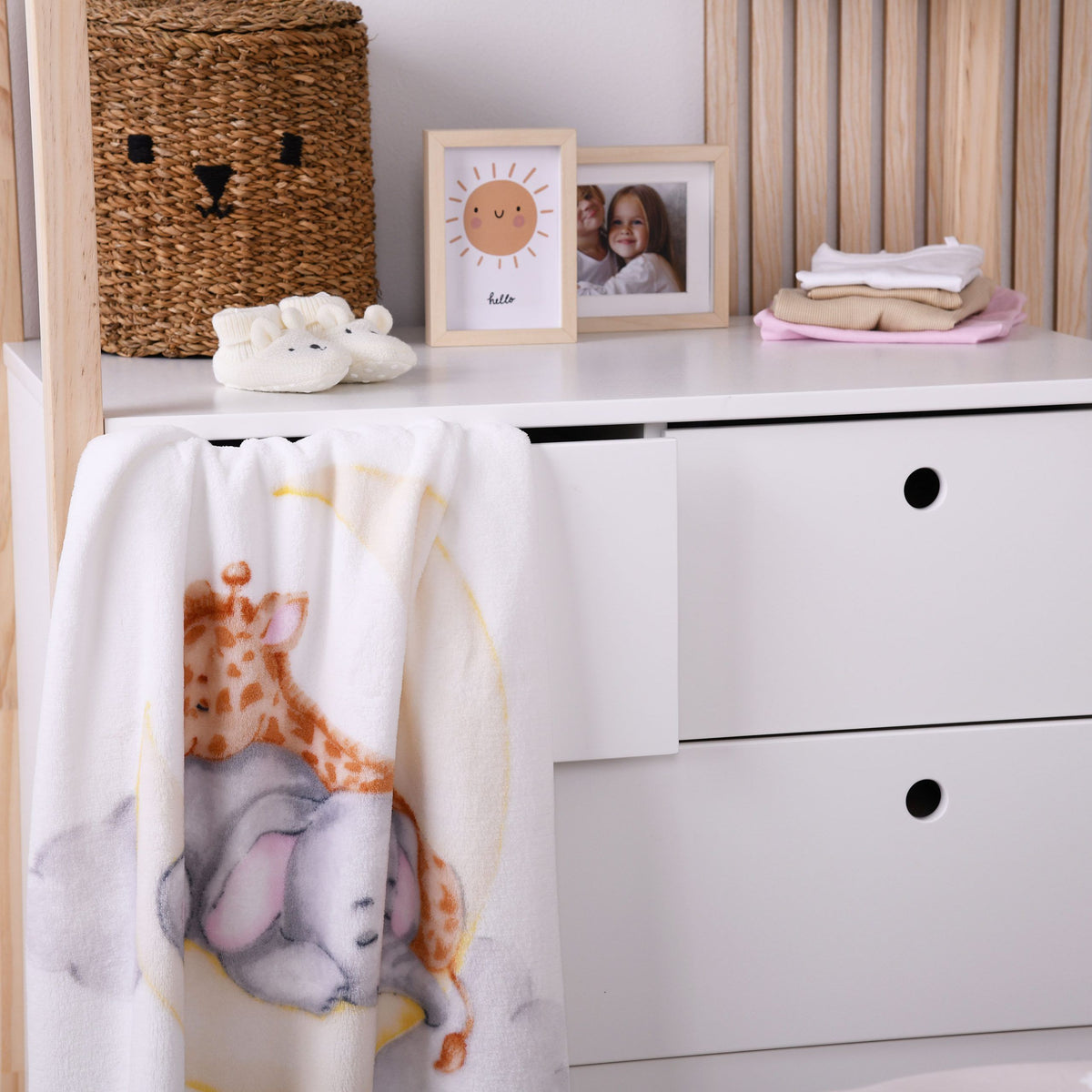 babybest Kuscheldecke ‘Sleeping on the Moon’ über einer weißen Kommode im Kinderzimmer