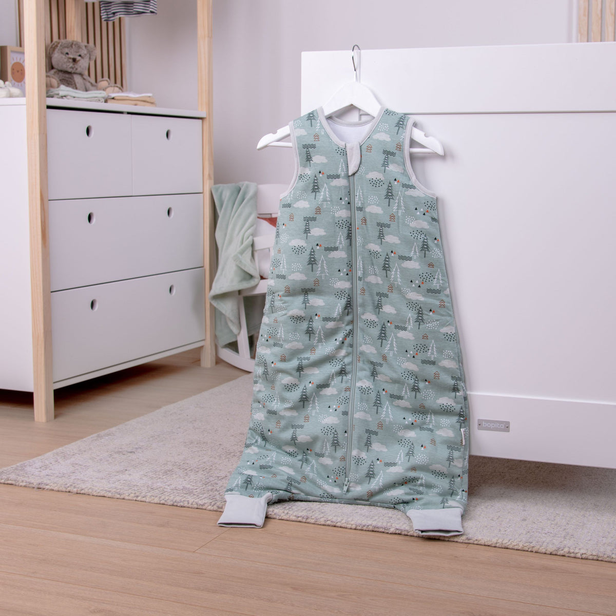 babybest Schlafoverall ‘Nordic Forest’ auf einem Bügel im Kinderzimmer