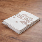 Zusammengelegte Strickdecke ‘Kleiner Lieblingsmensch’ mit Schriftzug auf einem Holzboden