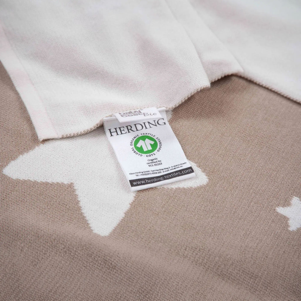 Etikett mit GOTS-Zeichen auf der Rückseite der Strickdecke in Taupe
