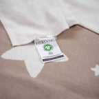Etikett mit GOTS-Zeichen auf der Rückseite der Strickdecke in Taupe