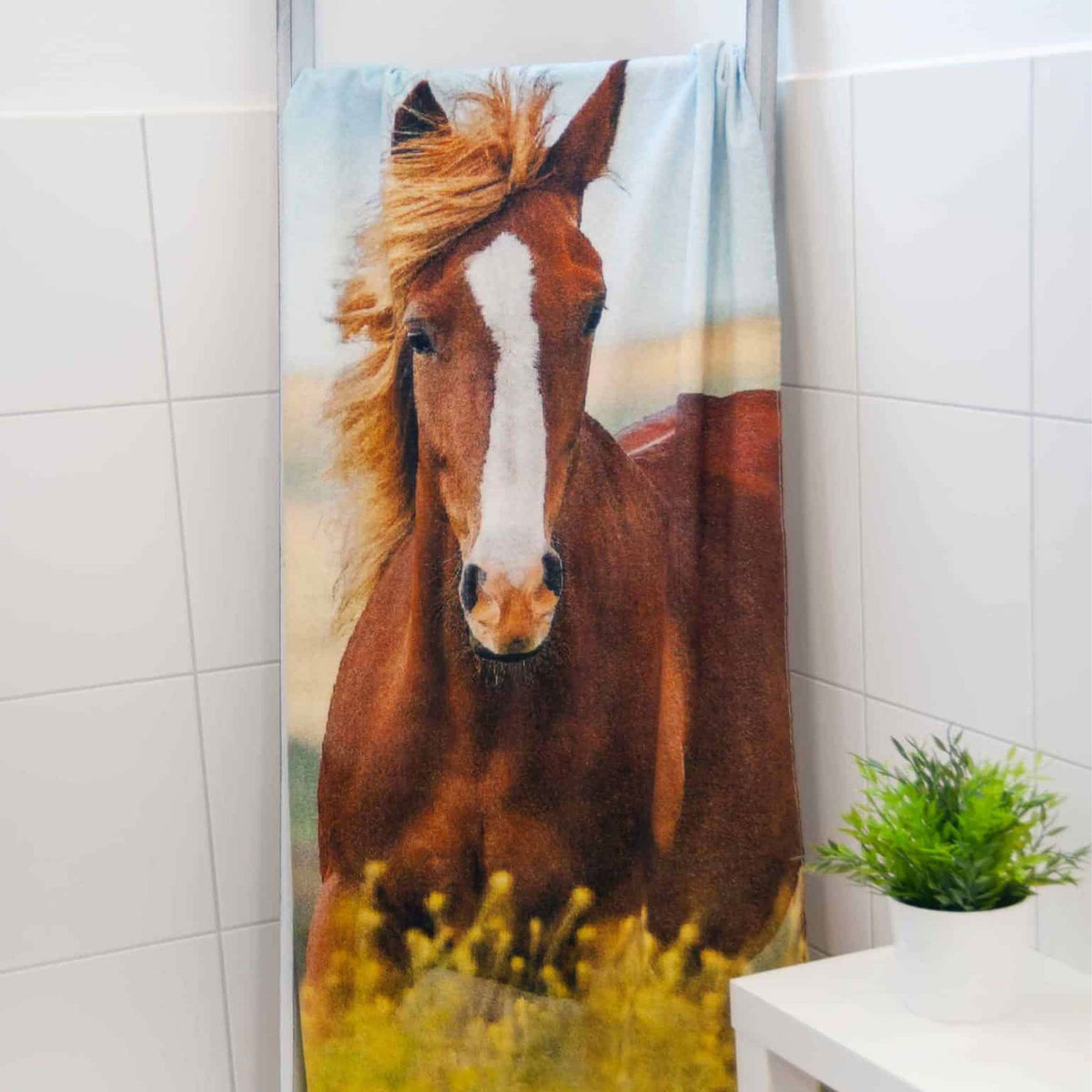 Badetuch ‘Pferd’ hängend im gefliesten Badezimmer neben einer Pflanze
