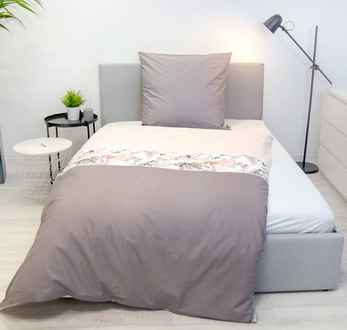 Bench Bettwäsche ‘Blumen’ frontal auf einem Bett mit grauem Kissen
