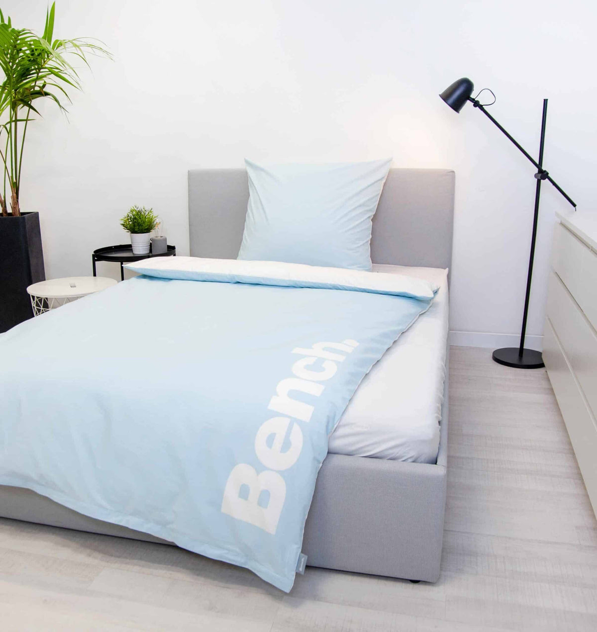 Bench Bettwäsche ‘Hellblau’ auf einem Bett, Logo am Bettbezug