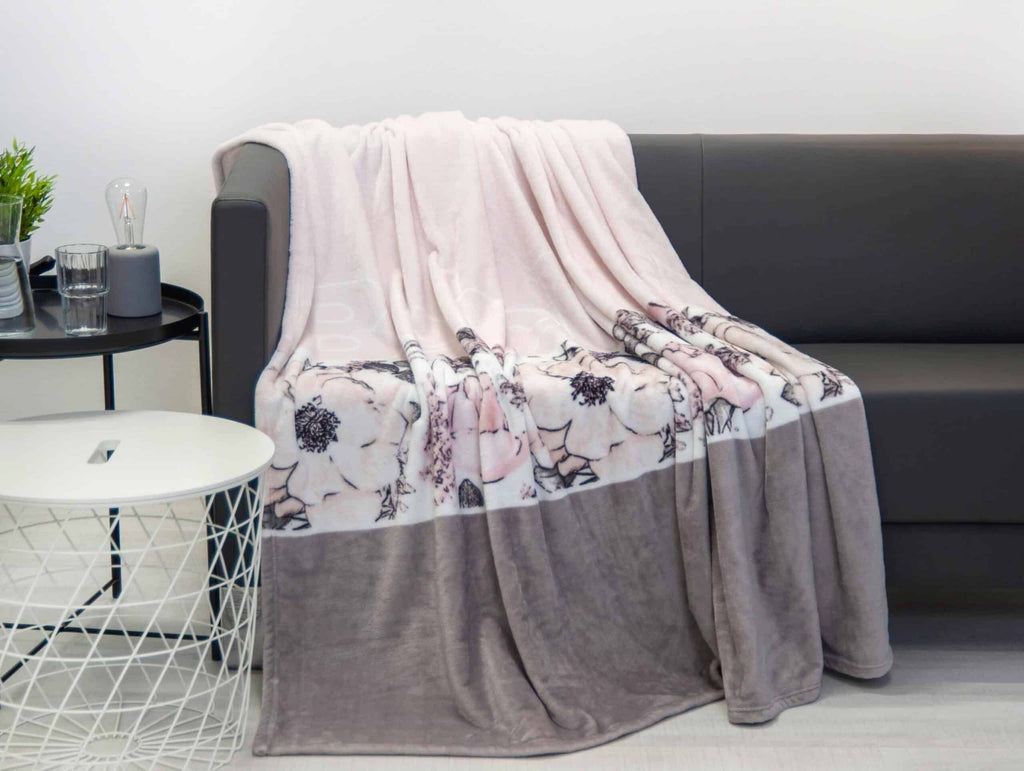 Bench Kuscheldecke im Design Blumen auf einem dunkelgrauen Sofa