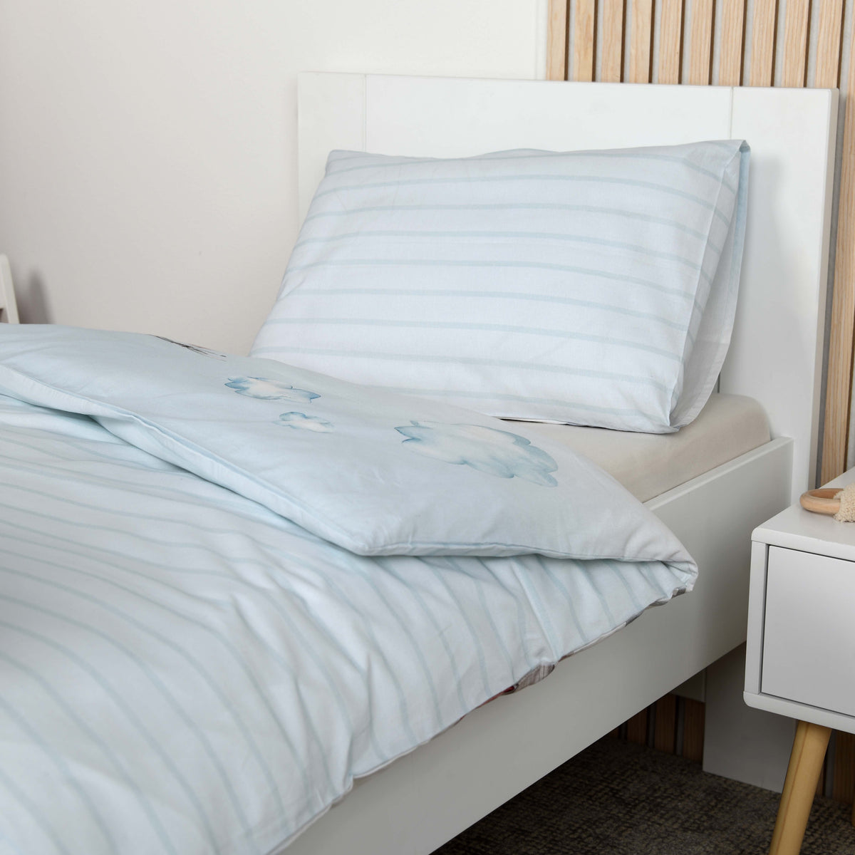 Hellblau gestreifte Wendeseite der Bettwäsche ‘Feuerwehr’ mit gestreifter Kissenseite auf einem Kinderbett
