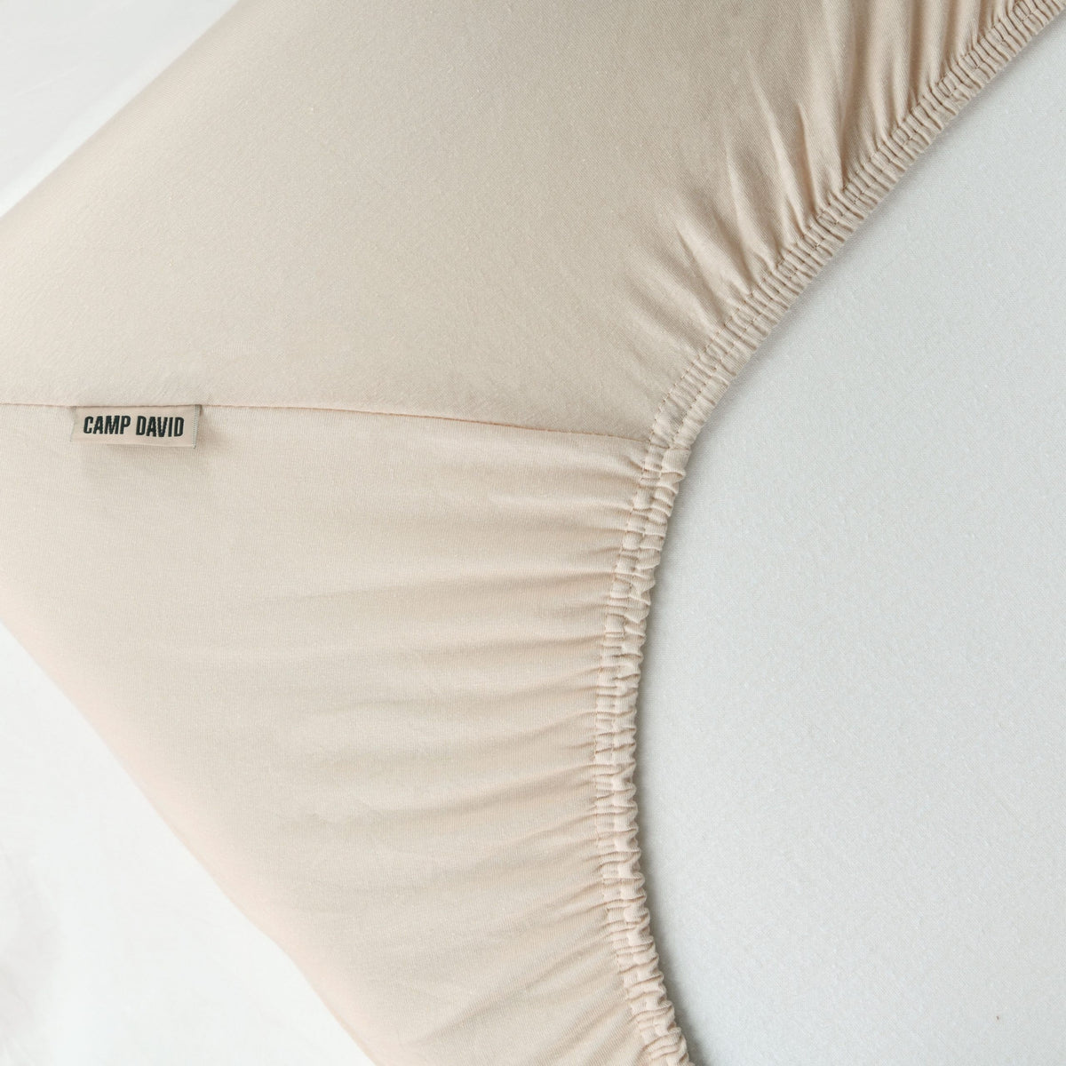 Ecke des CAMP DAVID Spannbettlakens in Beige mit Gummizug und Etikett auf einer Matratze