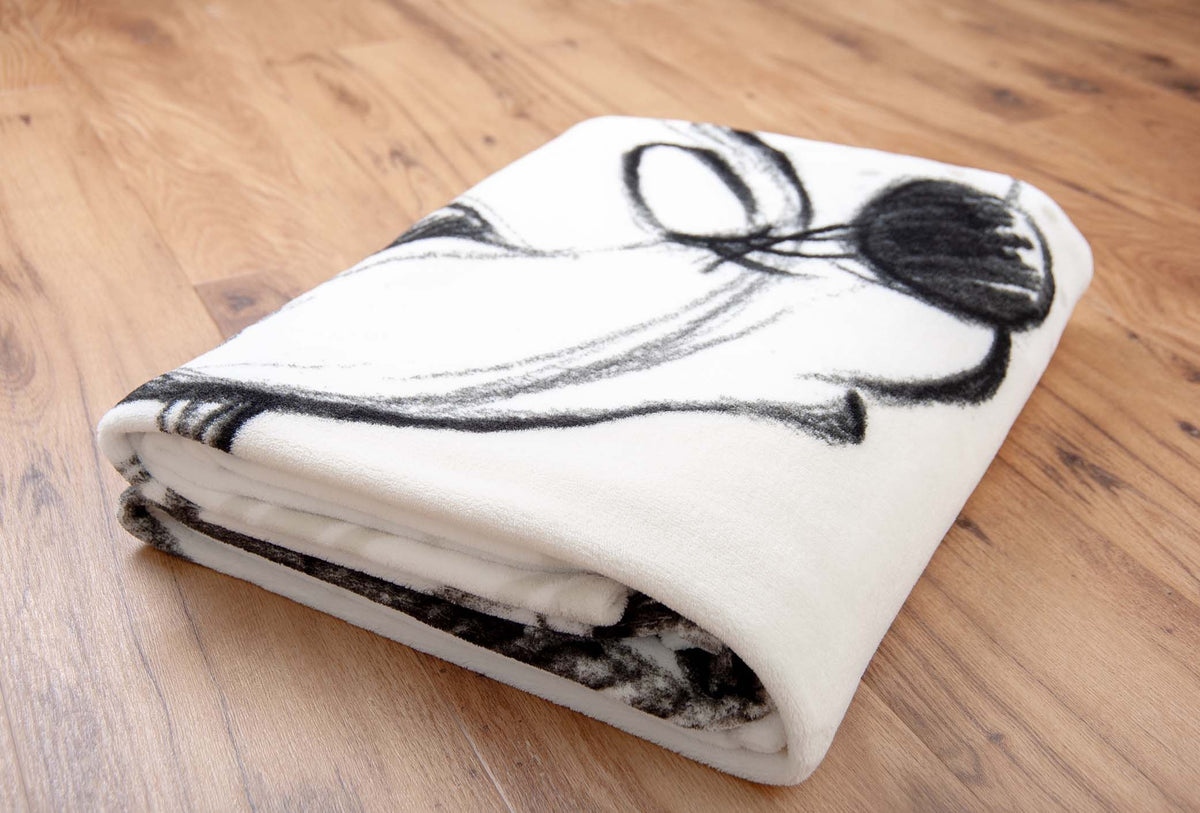 Zusammengelegte Kuscheldecke ‘Love’ auf dem Holzboden