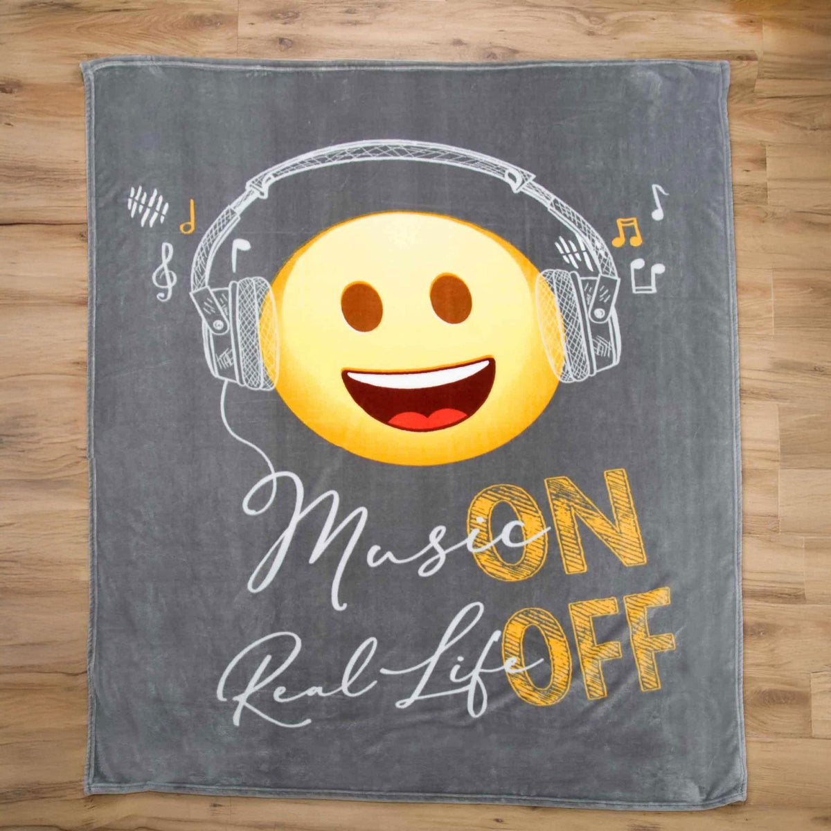 Emot!x Kuscheldecke ‘Music’ ausgebreitet auf einem Holzboden