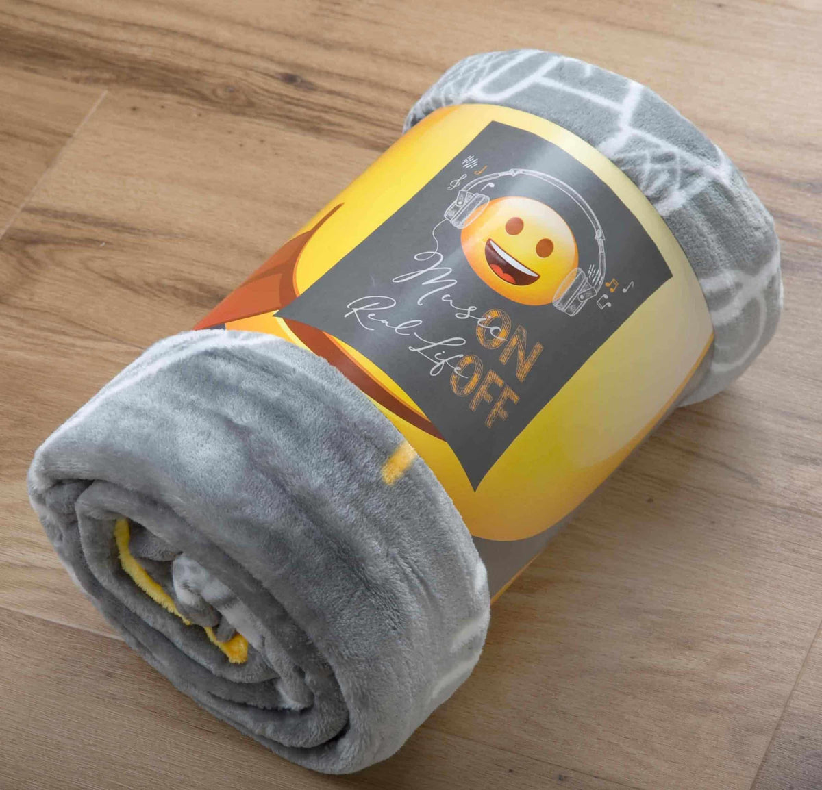 Aufgerollte Emot!x Kuscheldecke mit Banderole