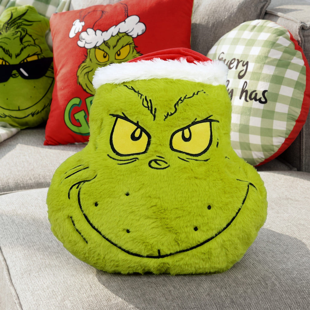 Grinch Formkissen ‘Merry Grinchmas’ auf grauem Sofa mit weiteren Grinch-Kissen