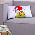 Grinch Kuschelkissen ‘Merry Grinchmas’ auf einem grauen Sofa, Vorderseite mit Grinch-Gesicht