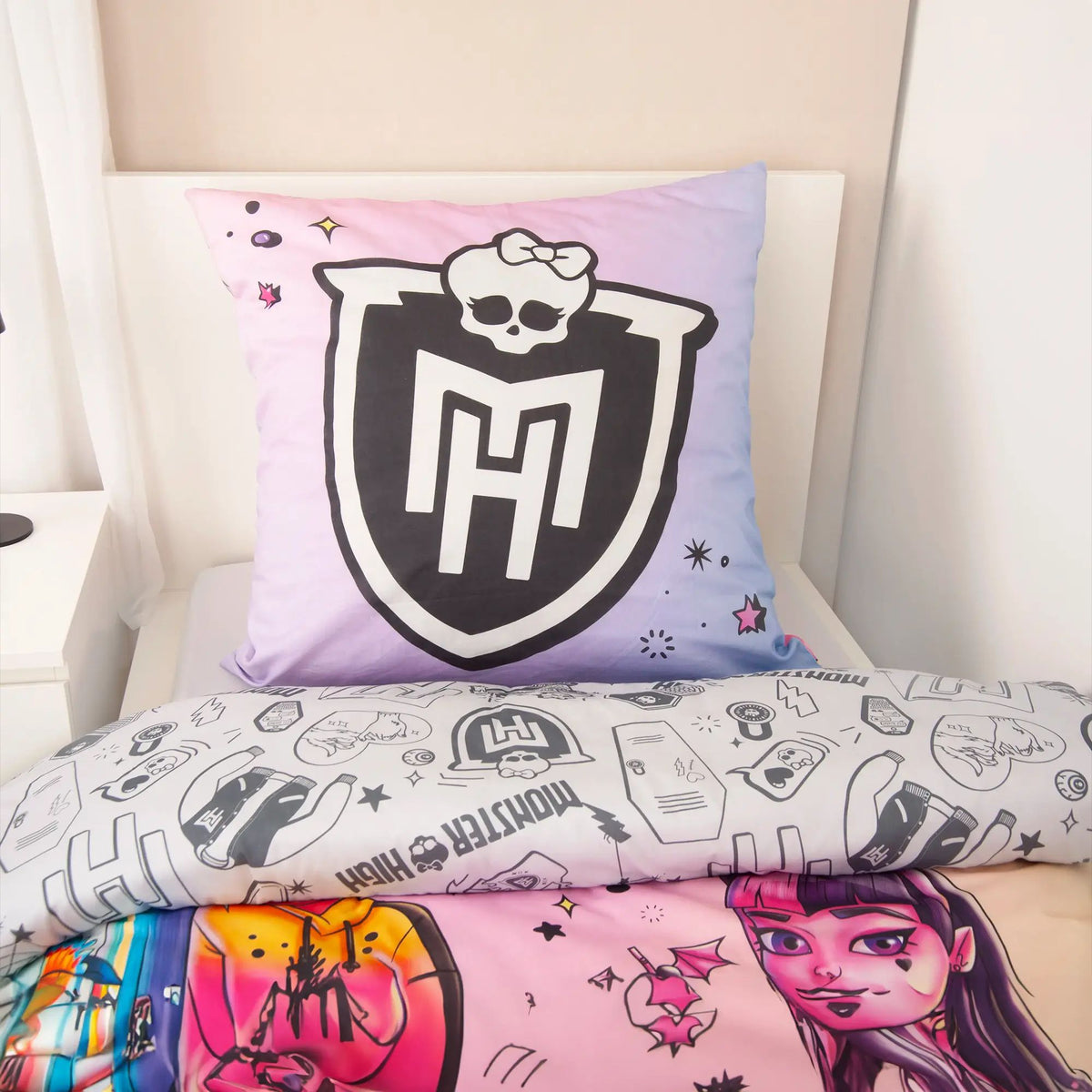 Kissen mit Monster-High-Wappen auf Lila und graue Wendeseite auf einem Bett