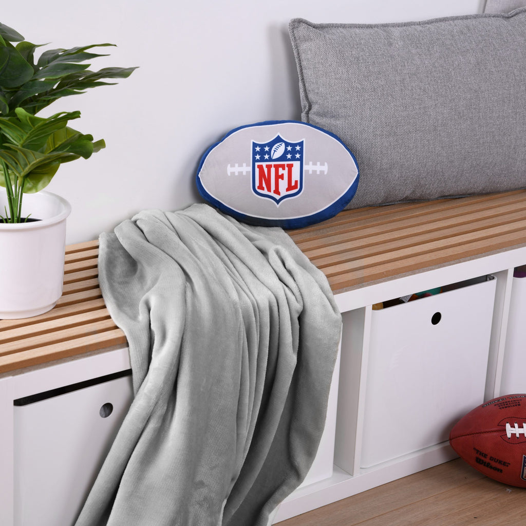 NFL Formkissen ‘Classic’ auf einer Holzbank mit grauer Kuscheldecke, davor ein Football