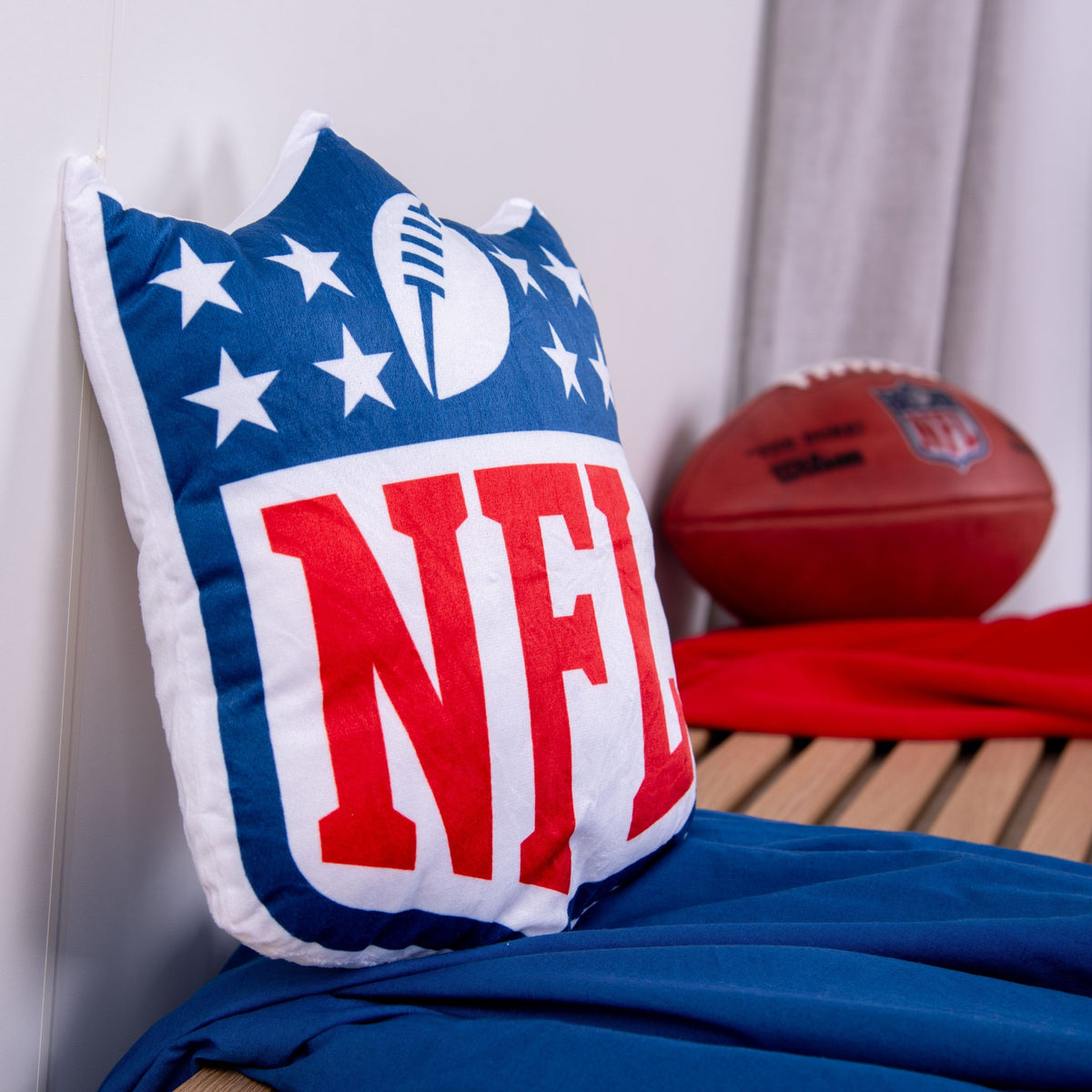 NFL Formkissen ‘Shield’ auf einer Holzbank, dahinter ein Football