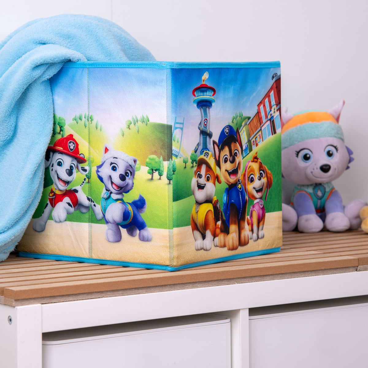 Paw Patrol Aufbewahrungsbox mit einer hellblauen Decke neben einer Plüschfigur