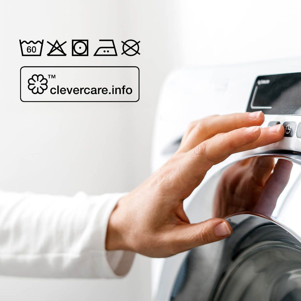 Pflegesymbole: 60 °C Maschinenwäsche, nicht bleichen, Trockner bei niedriger Temperatur, mäßig heiß bügeln, nicht chemisch reinigen