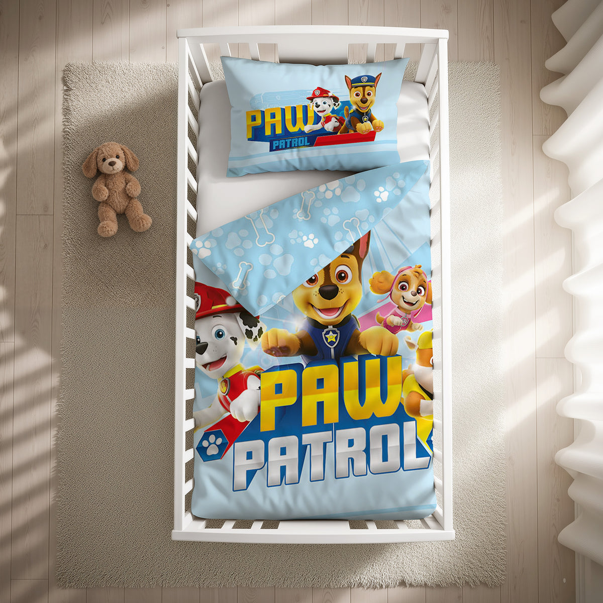 Paw Patrol Kleinkindbettwäsche-Set ‘Blue Mission’ 100 x 135 cm mit Kissenbezug 40 x 60 cm im Gitterbett, Draufsicht mit umgeschlagener Wendeseite mit Pfoten und Knochen