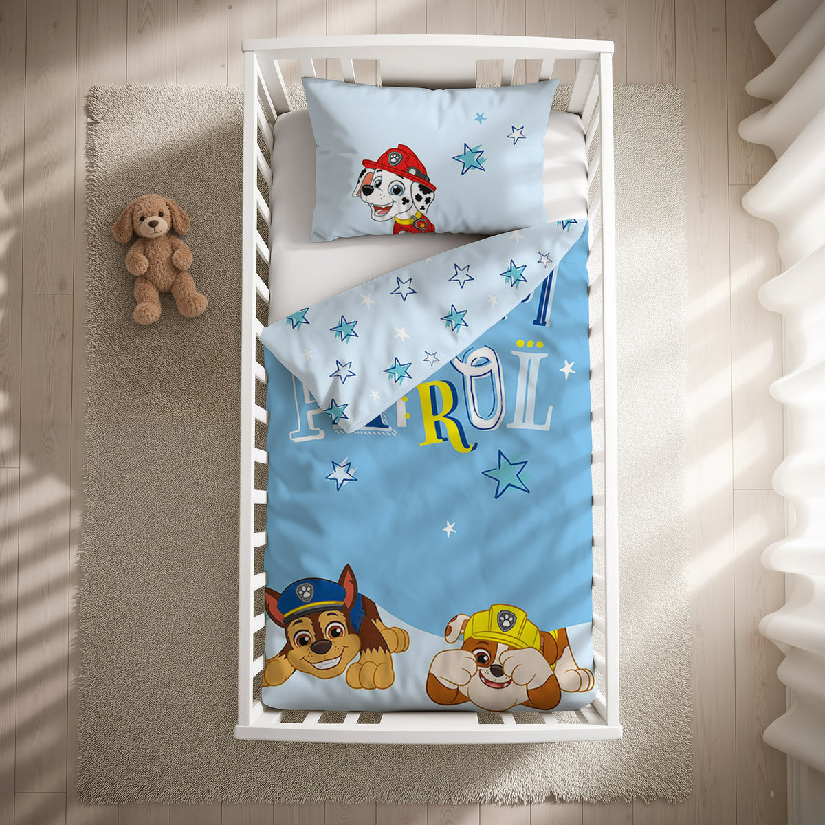 Paw Patrol Kleinkindbettwäsche-Set ‘Blue Star’ 100 x 135 cm mit Kissenbezug 40 x 60 cm im Gitterbett, Draufsicht mit umgeschlagener Sternen-Wendeseite