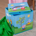 Peppa Wutz Aufbewahrungsbox mit einer zweiten, flach gefalteten Box obenauf, daneben eine grüne Decke
