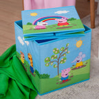 Peppa Wutz Aufbewahrungsbox mit einer zweiten, flach gefalteten Box obenauf, daneben eine grüne Decke