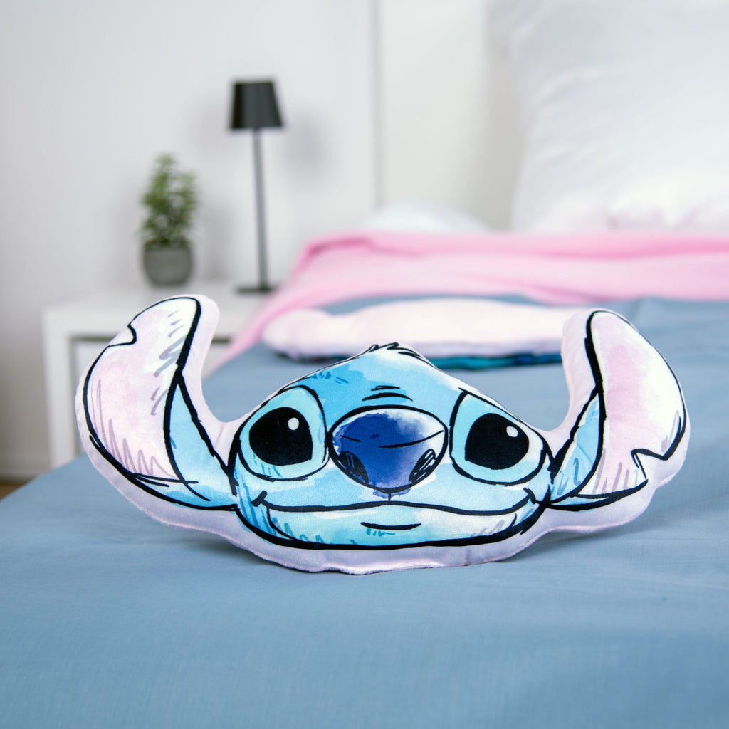Stitch Kuschelkissen auf einem Bett mit blaugrauer Bettwäsche und rosa Decke