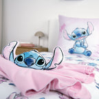 Stitch Kuschelkissen auf einer rosa Decke, dahinter Bettwäsche mit Stitch