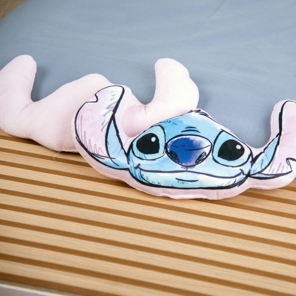 Stitch Kuschelkissen neben der zartrosa Rückseite eines zweiten Kissens auf der Holzbank