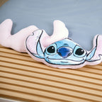 Stitch Kuschelkissen neben der zartrosa Rückseite eines zweiten Kissens auf der Holzbank