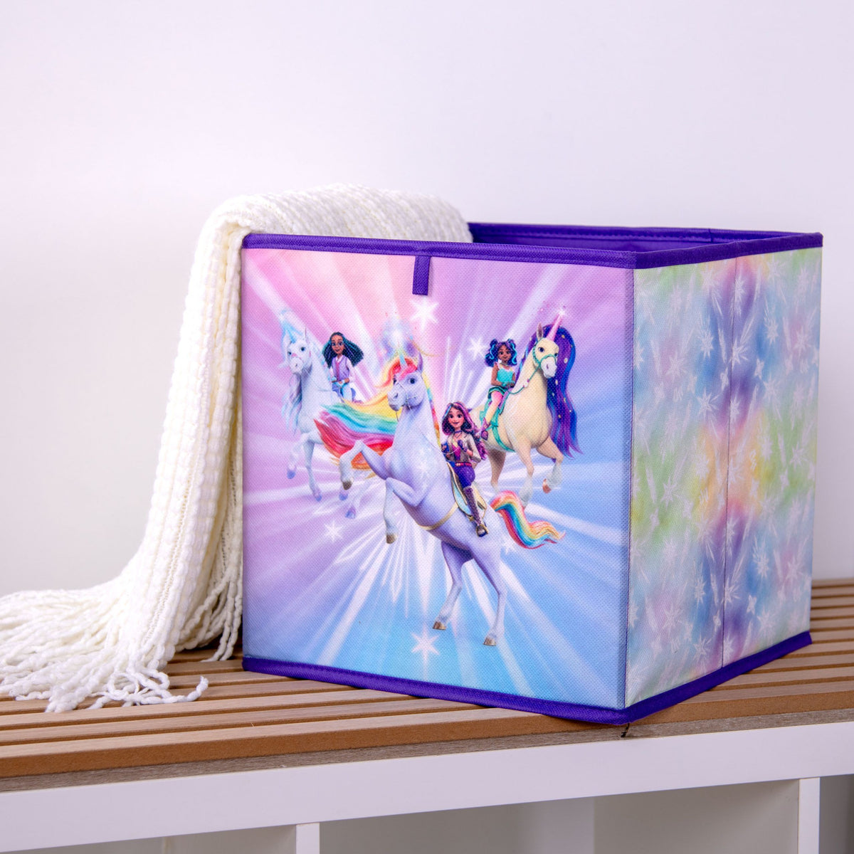 Unicorn Academy Aufbewahrungsbox auf einer Holzbank, darüber eine Strickdecke