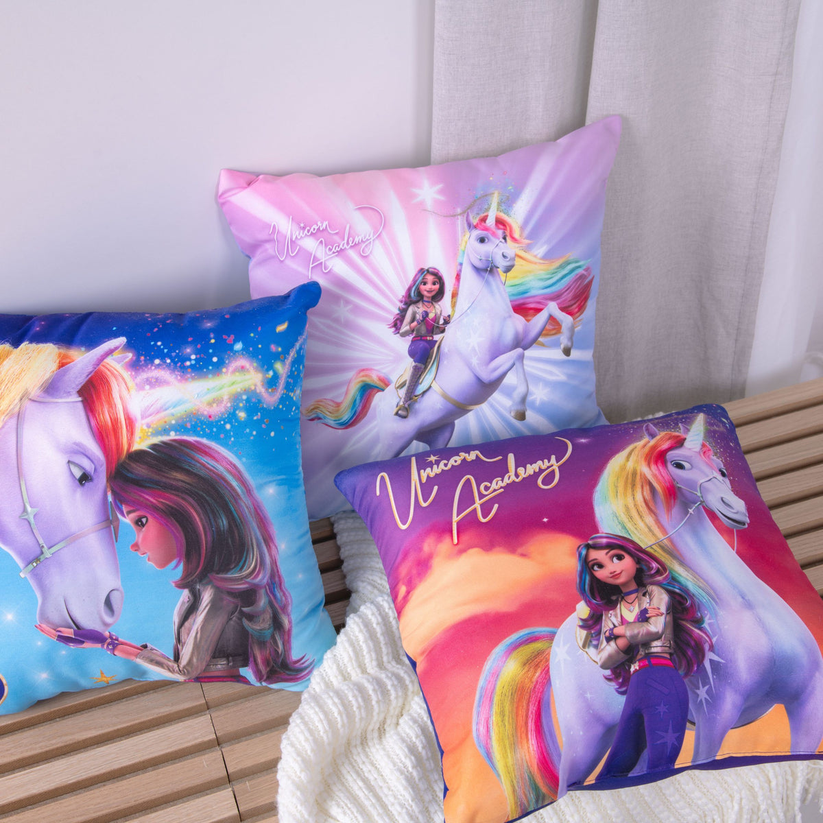 Unicorn Academy Dekokissen-Set ‘Magic’ auf einer Holzbank mit heller Strickdecke